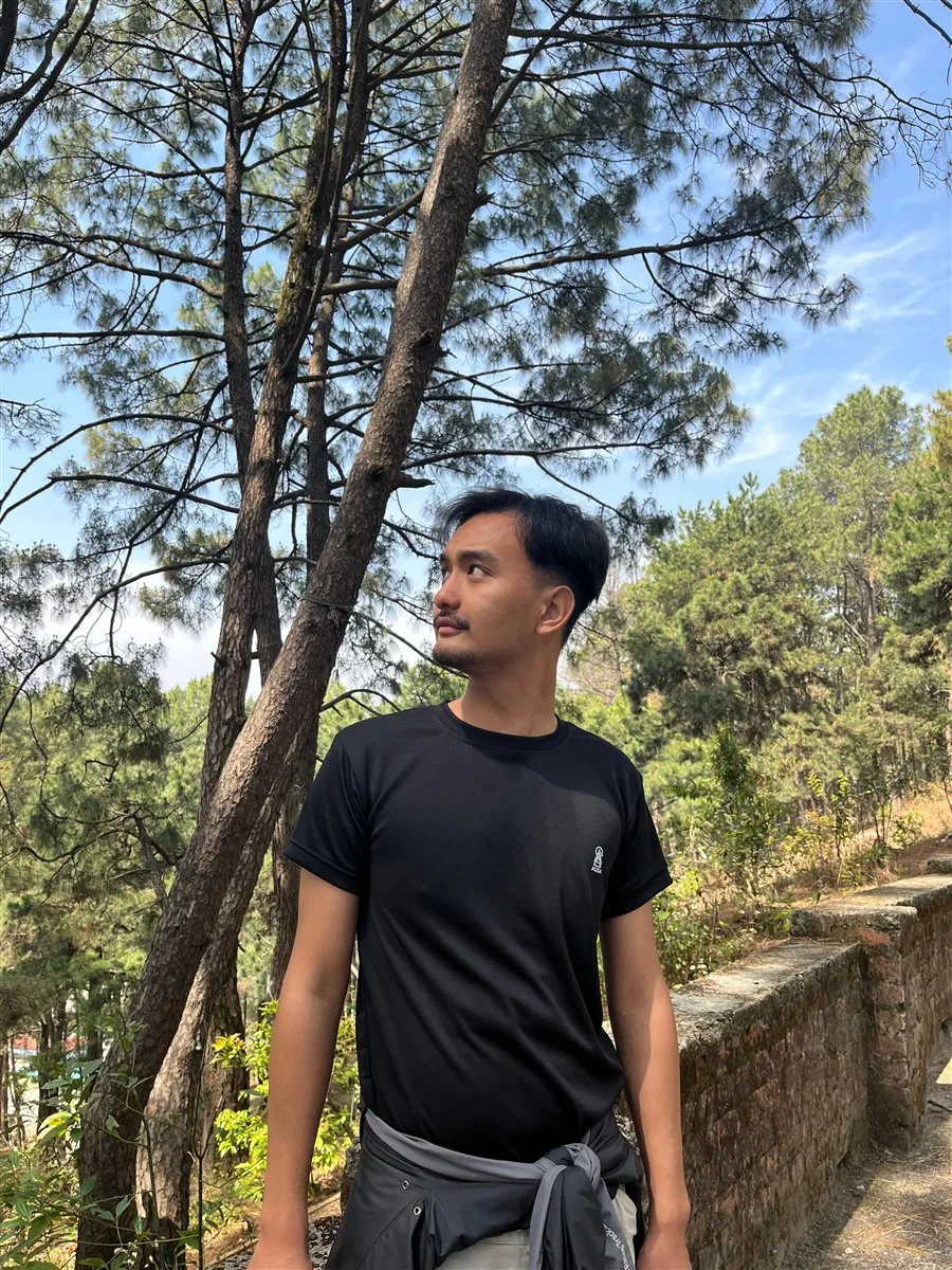 Ninson Lama standing in a pine forest